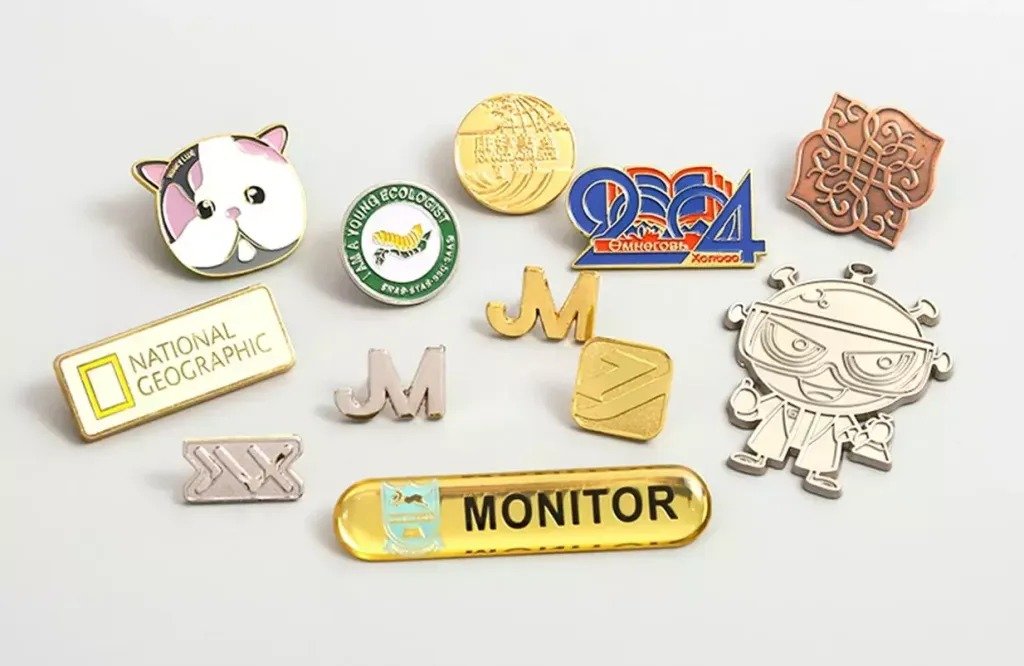 Collection of custom metal badges and logo pins in soft enamel, hard enamel, die struck and epoxy dome crafts